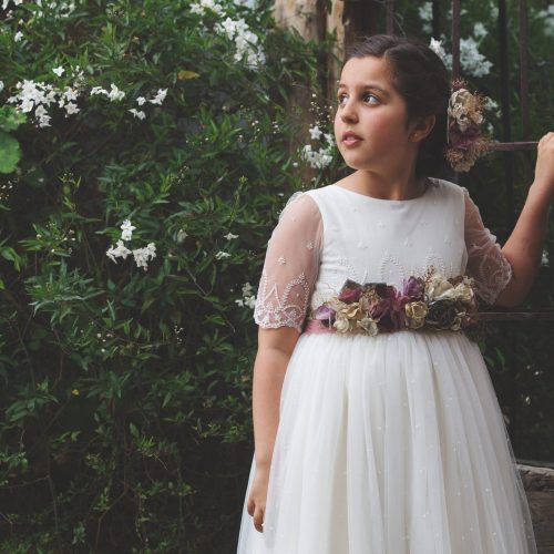 Sesión de comunión en exterior con niña rodeada de flores silvestres