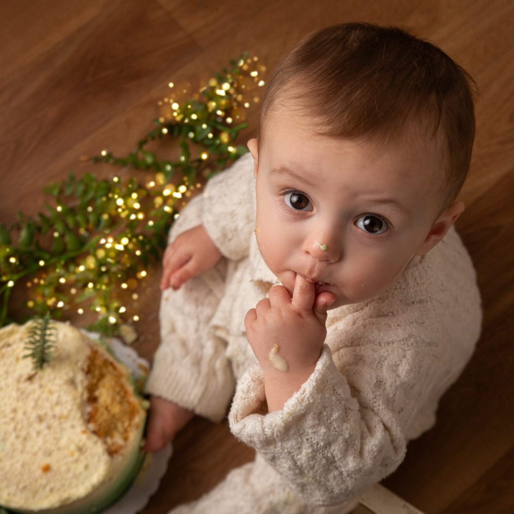 Fotografía de primer cumpleaños con niño y decoración navideña en estudio