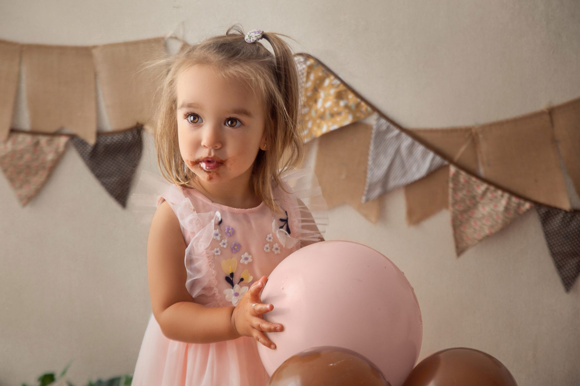Niña en sesión smash cake de 2 años con decoración en tonos rosas