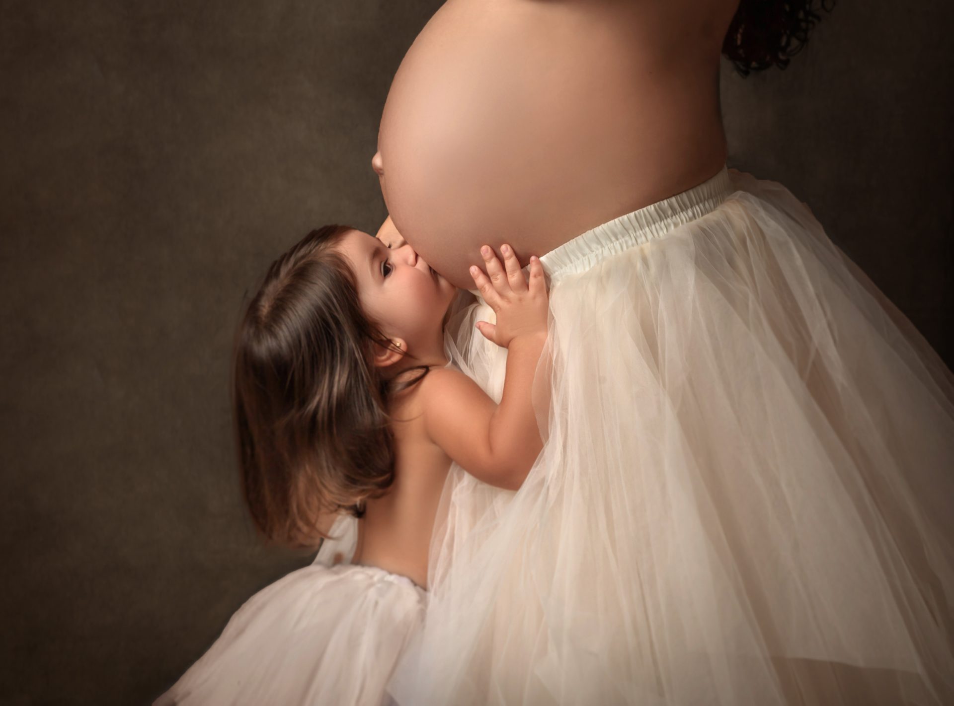 niña besando a su hermano en sesión elegante en estudio