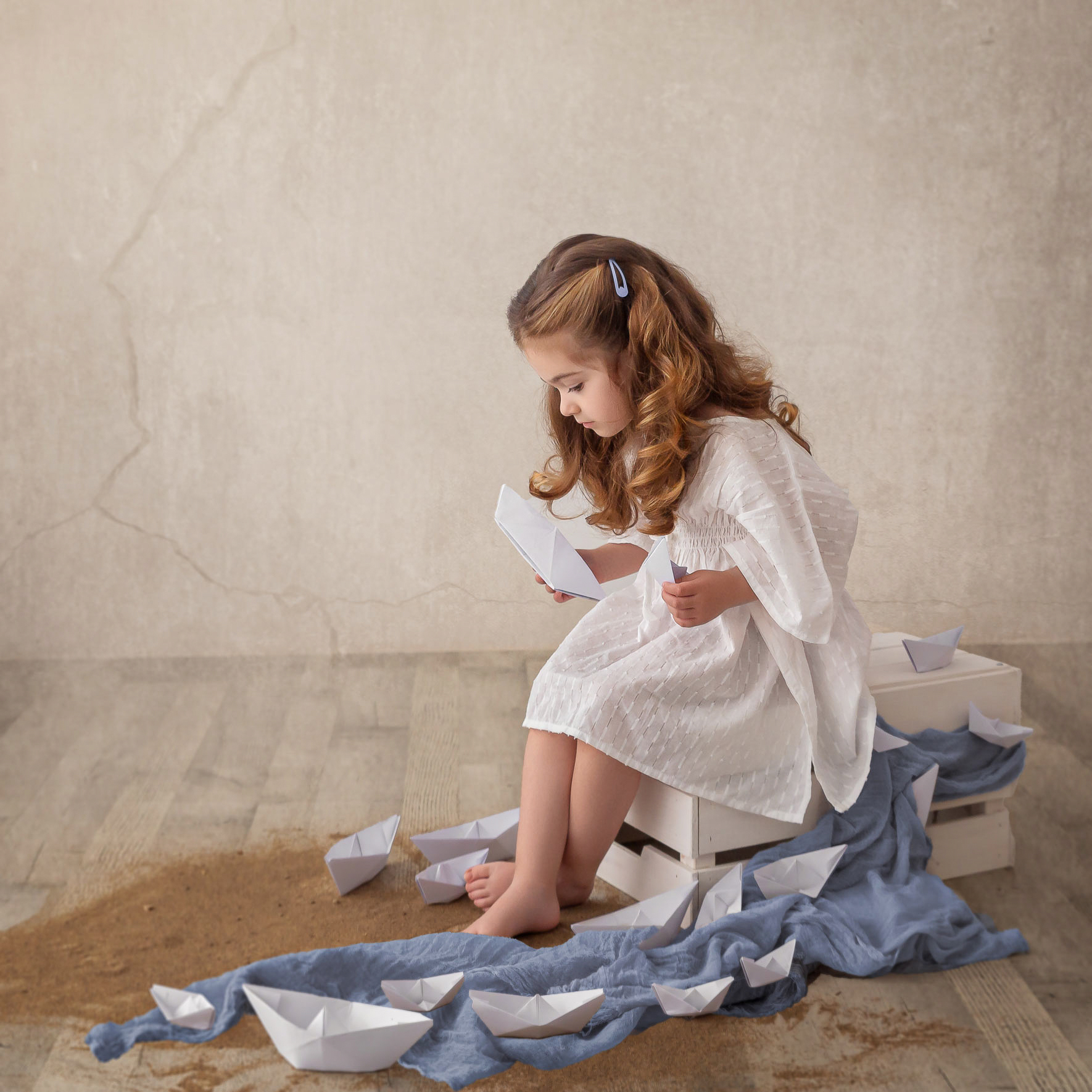 Niña en sesión de verano en Barakaldo jugando con barcos de papel