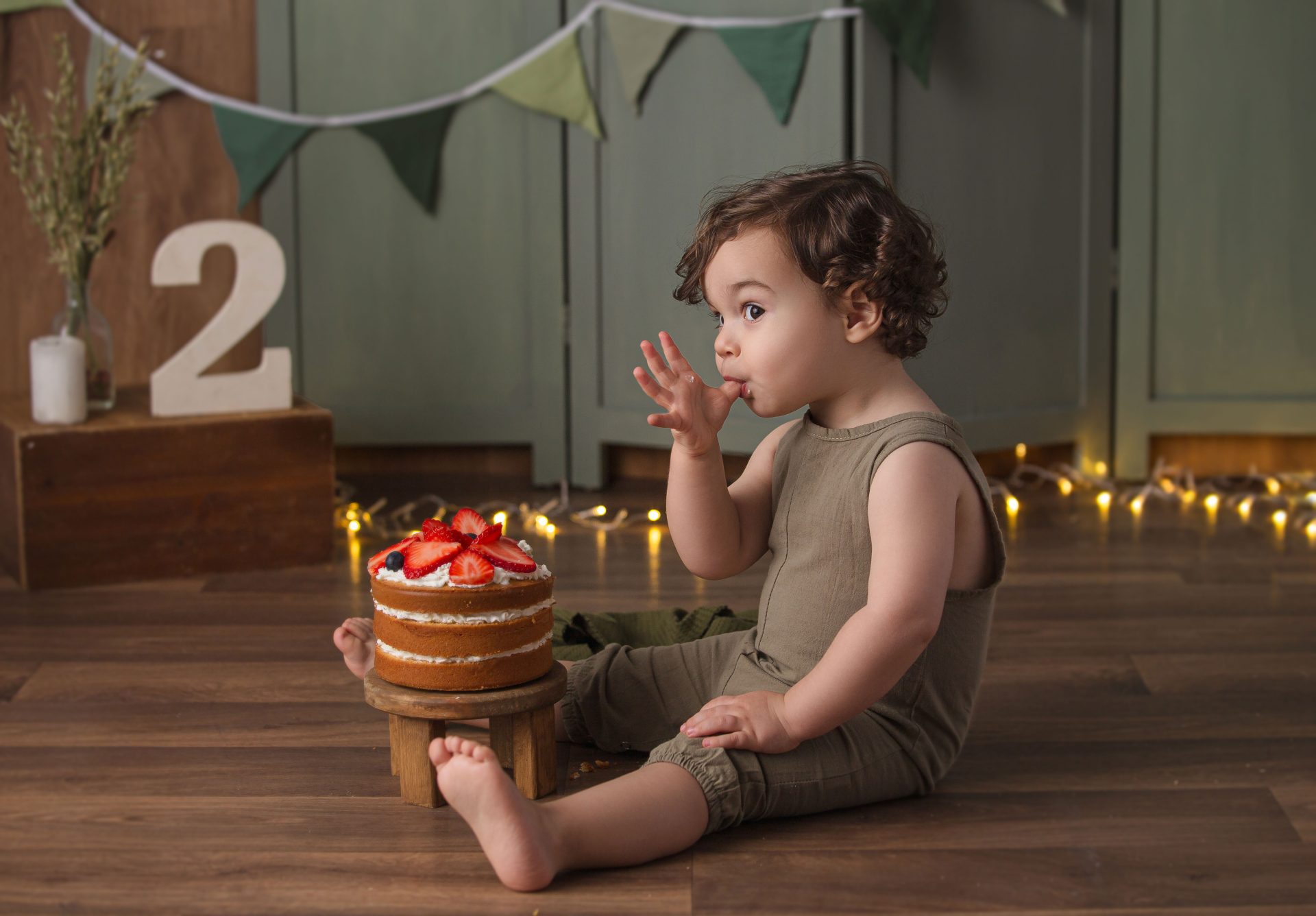 Retrato de niño de dos años en sesión smash cake temática verde