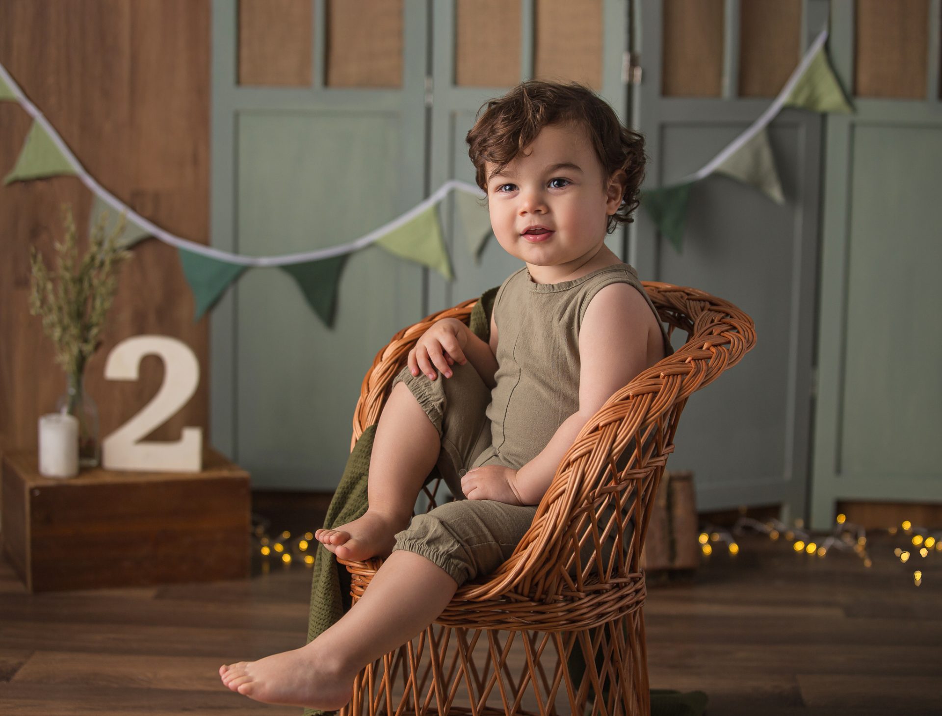 Niño sentado en escenario para sesión smash cake en tonos verdes