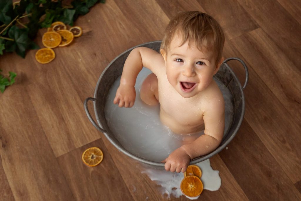 Bebé disfrutando sesión milk bath en bañera con frutas naturales