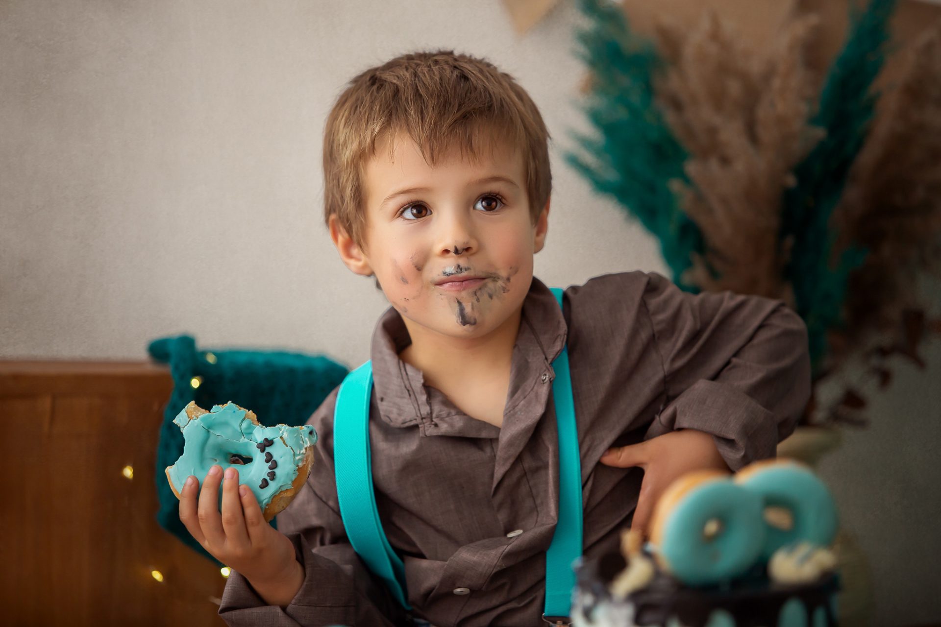Niño disfrutando sesión smash cake con colores variados y decoración temática